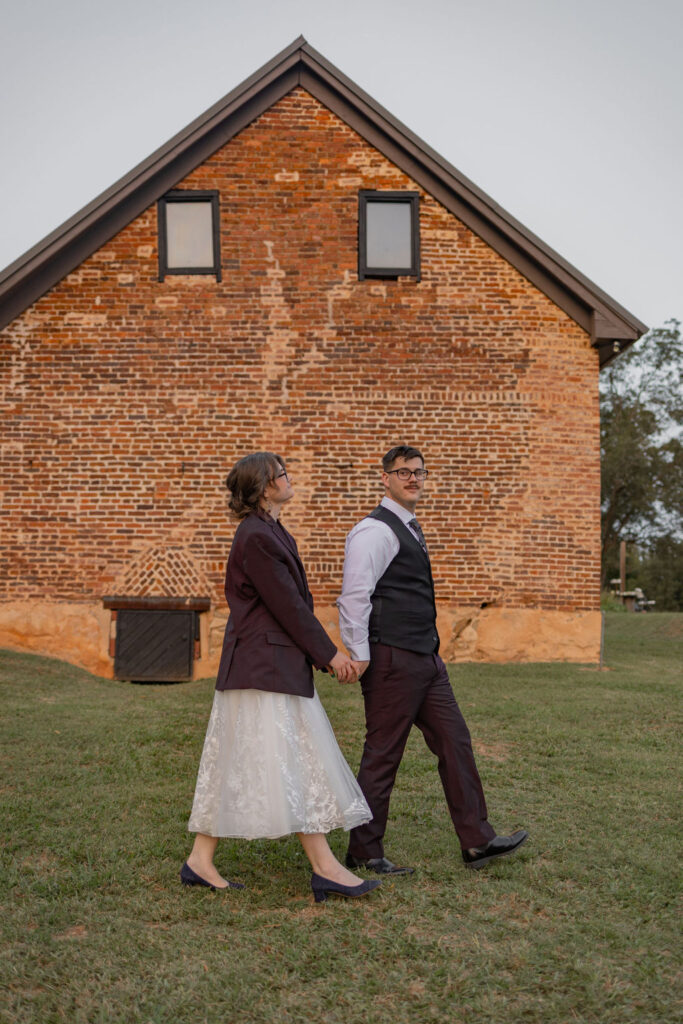 bride and groom walking outside barn at The Whiskey Bonding Farmy by Amanda Richardson Photography