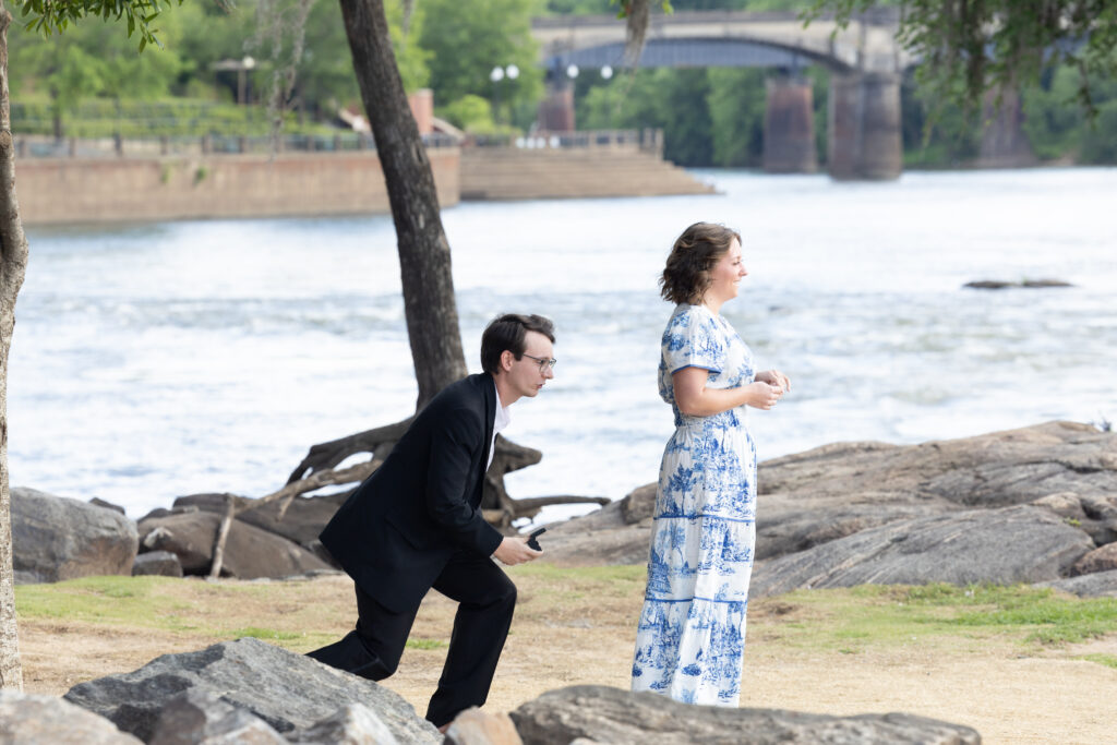 man proposing to woman with river in the background at sunset